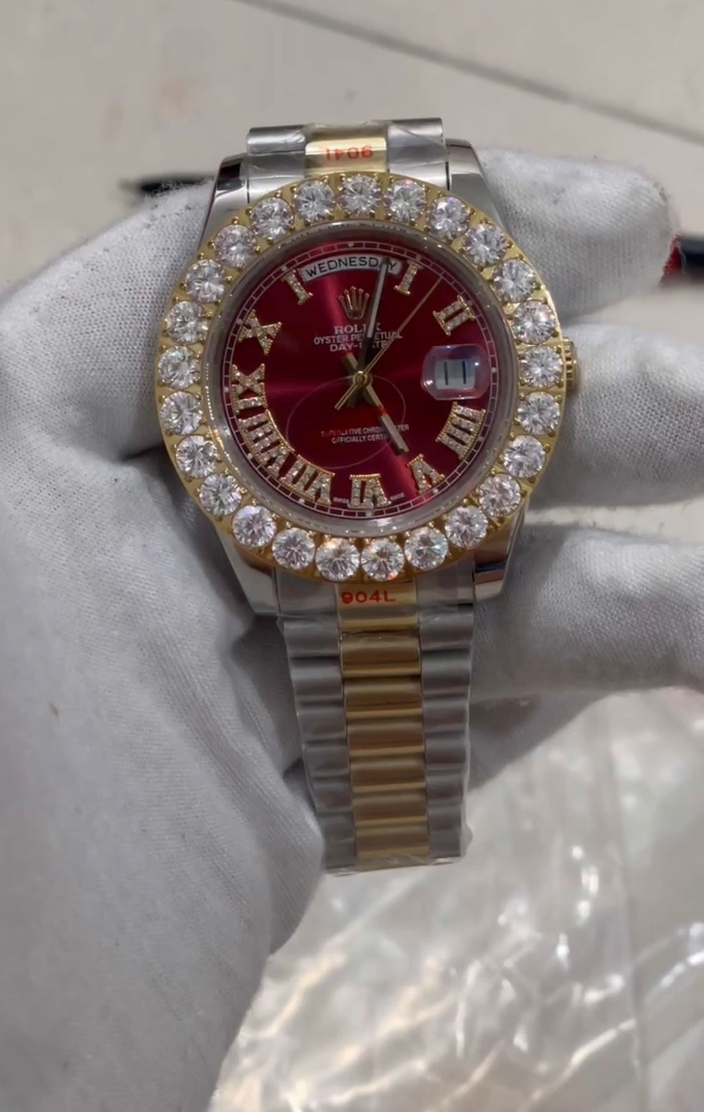 Rolex Day-Date or Datejust watch featuring a distinctive red dial and a custom aftermarket diamond bezel