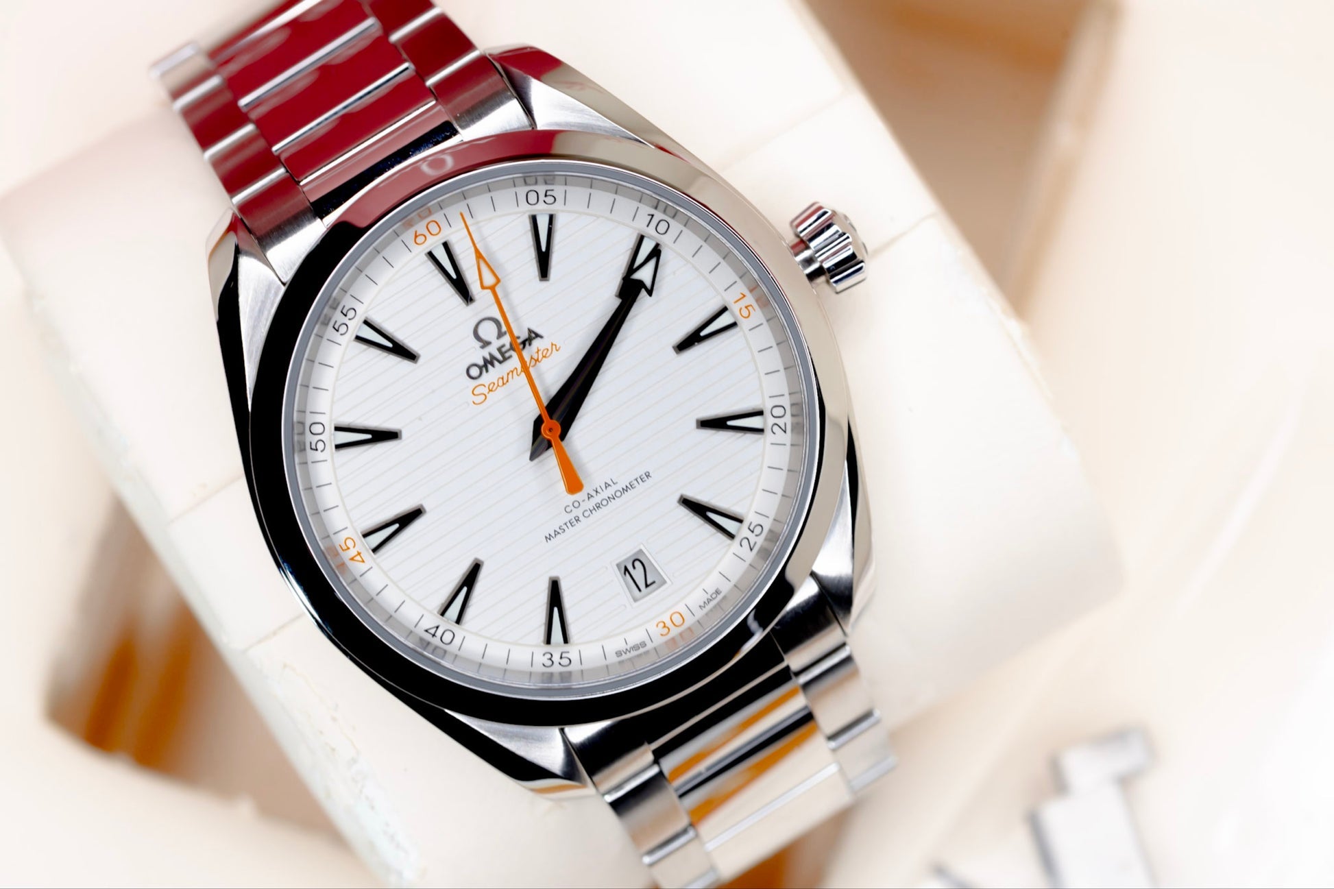 Omega Seamaster Aqua Terra 150M with a white horizontal teak-patterned dial and prominent orange accents