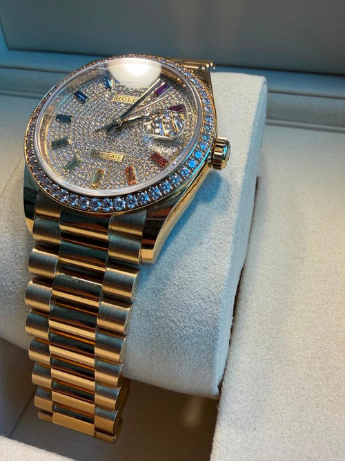 Rolex Day-Date 36mm in yellow gold, featuring a diamond-paved dial with rainbow sapphire markers
