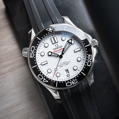 Omega Seamaster Diver 300M features a striking white ceramic dial with a distinctive wave pattern and a durable black rubber strap
