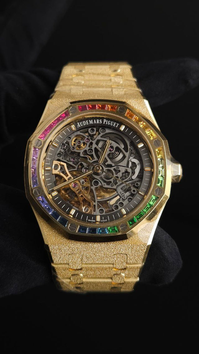 Audemars Piguet Royal Oak Double Balance Wheel Open-worked features a frosted yellow gold finish and a bezel set with rainbow-colored baguette-cut sapphires