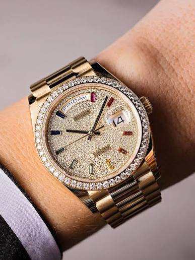 Rolex Day-Date 36mm in yellow gold, featuring a diamond-paved dial with rainbow sapphire markers