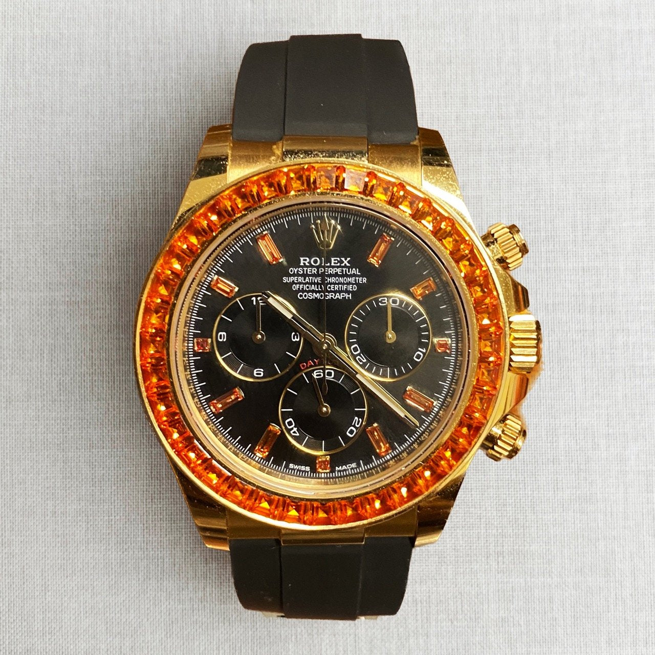 Rolex Cosmograph Daytona features yellow gold case and a bezel set with baguette-cut orange sapphires