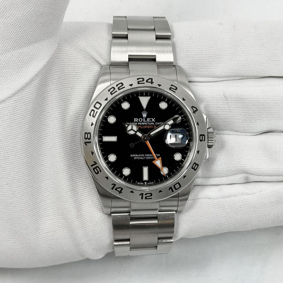 Rolex Explorer II, featuring a black dial, fixed steel bezel, and a distinctive orange GMT hand