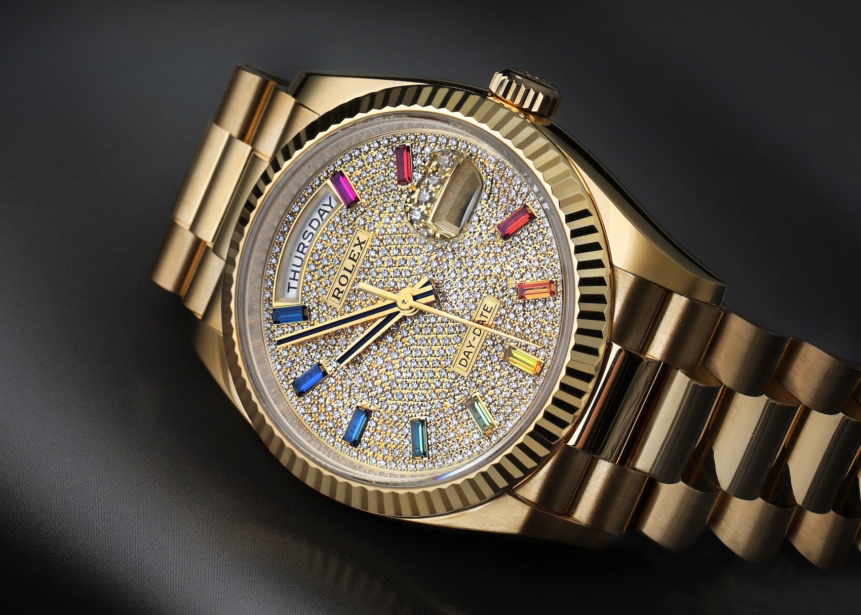 Rolex Day-Date 36mm in yellow gold, featuring a diamond-paved dial with rainbow sapphire markers