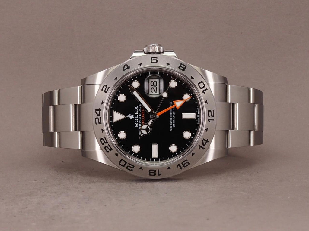 Rolex Explorer II, featuring a black dial, fixed steel bezel, and a distinctive orange GMT hand