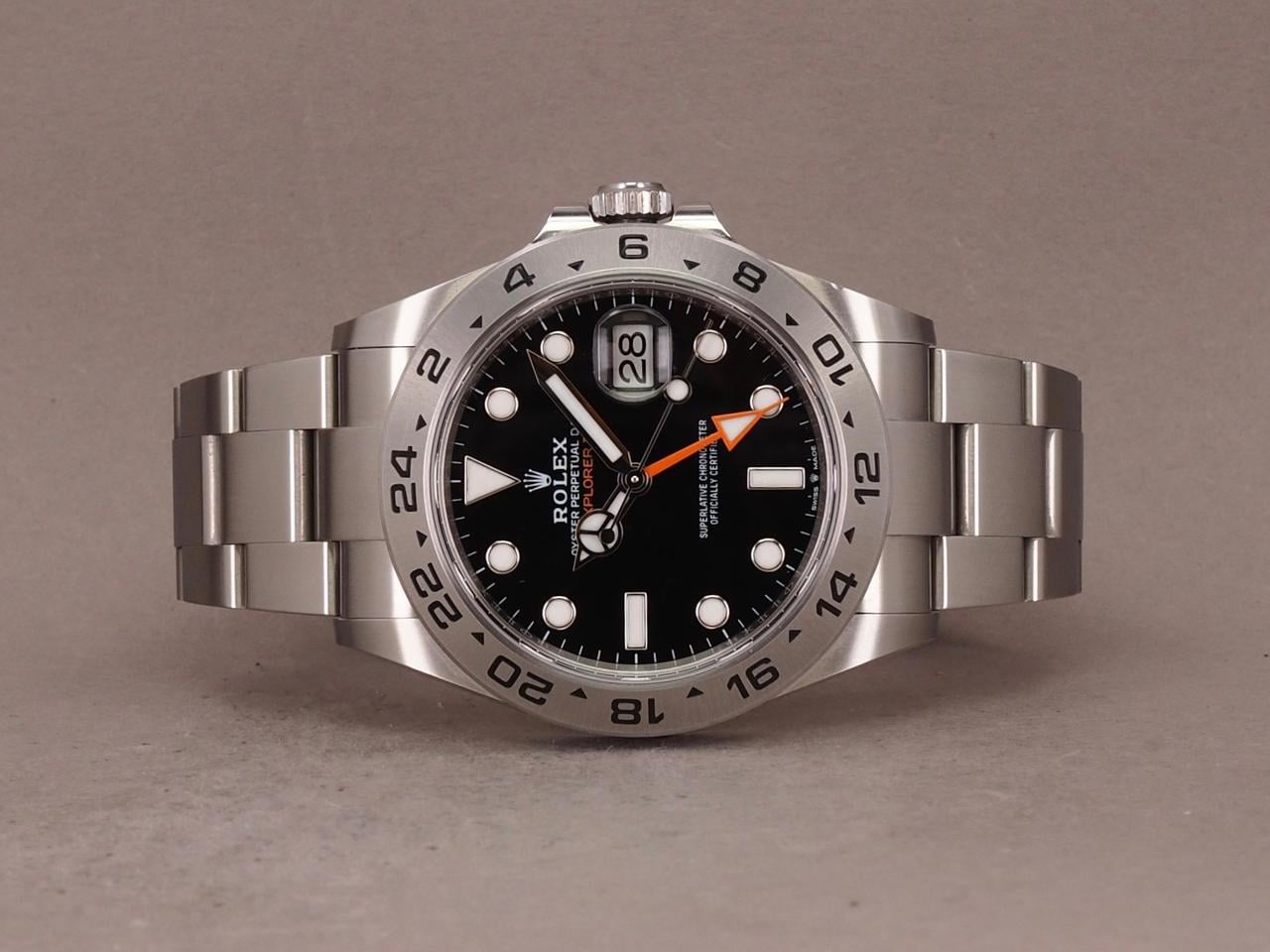 Rolex Explorer II, featuring a black dial, fixed steel bezel, and a distinctive orange GMT hand