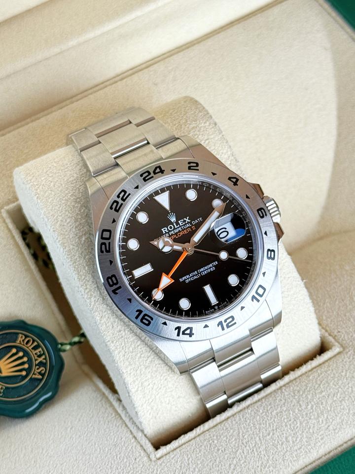Rolex Explorer II, featuring a black dial, fixed steel bezel, and a distinctive orange GMT hand