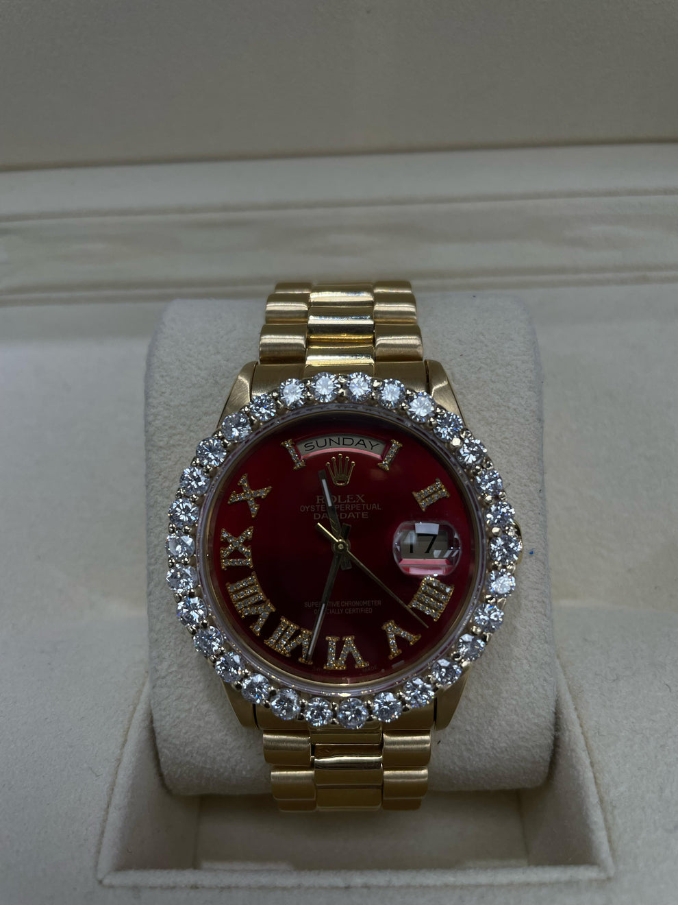 Rolex Day-Date or Datejust watch featuring a distinctive red dial and a custom aftermarket diamond bezel